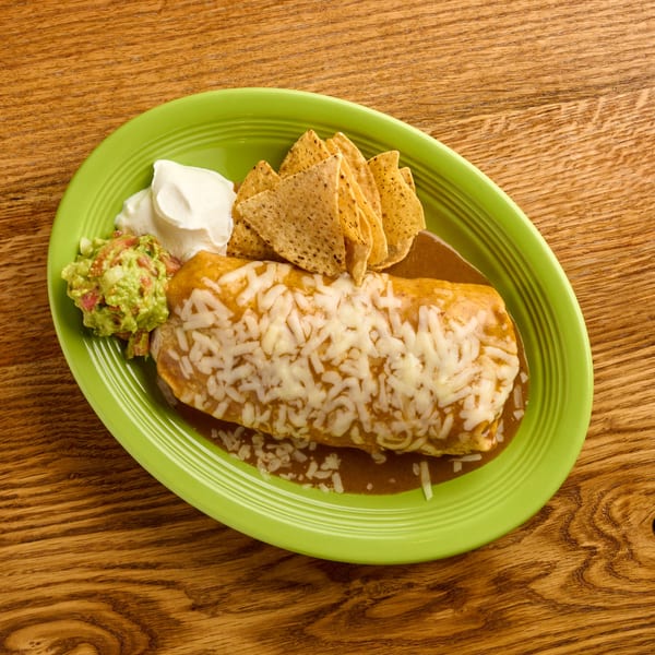 Salsaria's burrito covered in cheese and sauce, with guacamole, sour cream, and tortilla chips.